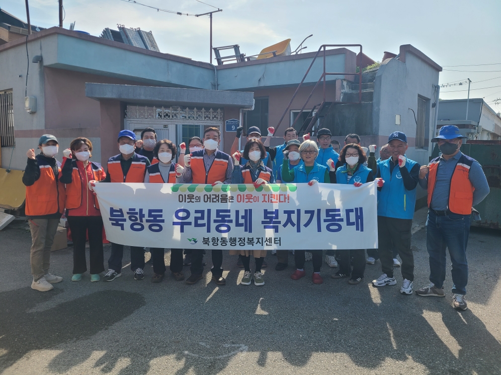 이웃의 어려움은 이웃이 지킨다! 북항동 우리동네 복지기동대 북항동행정복지센터 문구가 적힌 현수막을 들고 있는  소 전문업체 목포희망드림센터와 북항동 지역사회보장협의체(위원장 최상식), 복지기동대원 등 20명의 사람들이 마스크를 끼고, 화이팅을 하며 찍은 단체사진