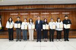 패 수여식에서 정장과 단정한 복장의 수상자들이 패를 들고 단체 기념 촬영을 하고 있는 모습이다.