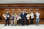 표창패 수여식에서 정장과 단정한 복장의 수상자들이 꽃다발과 패를 들고 단체 기념 촬영을 하고 있는 모습이다.